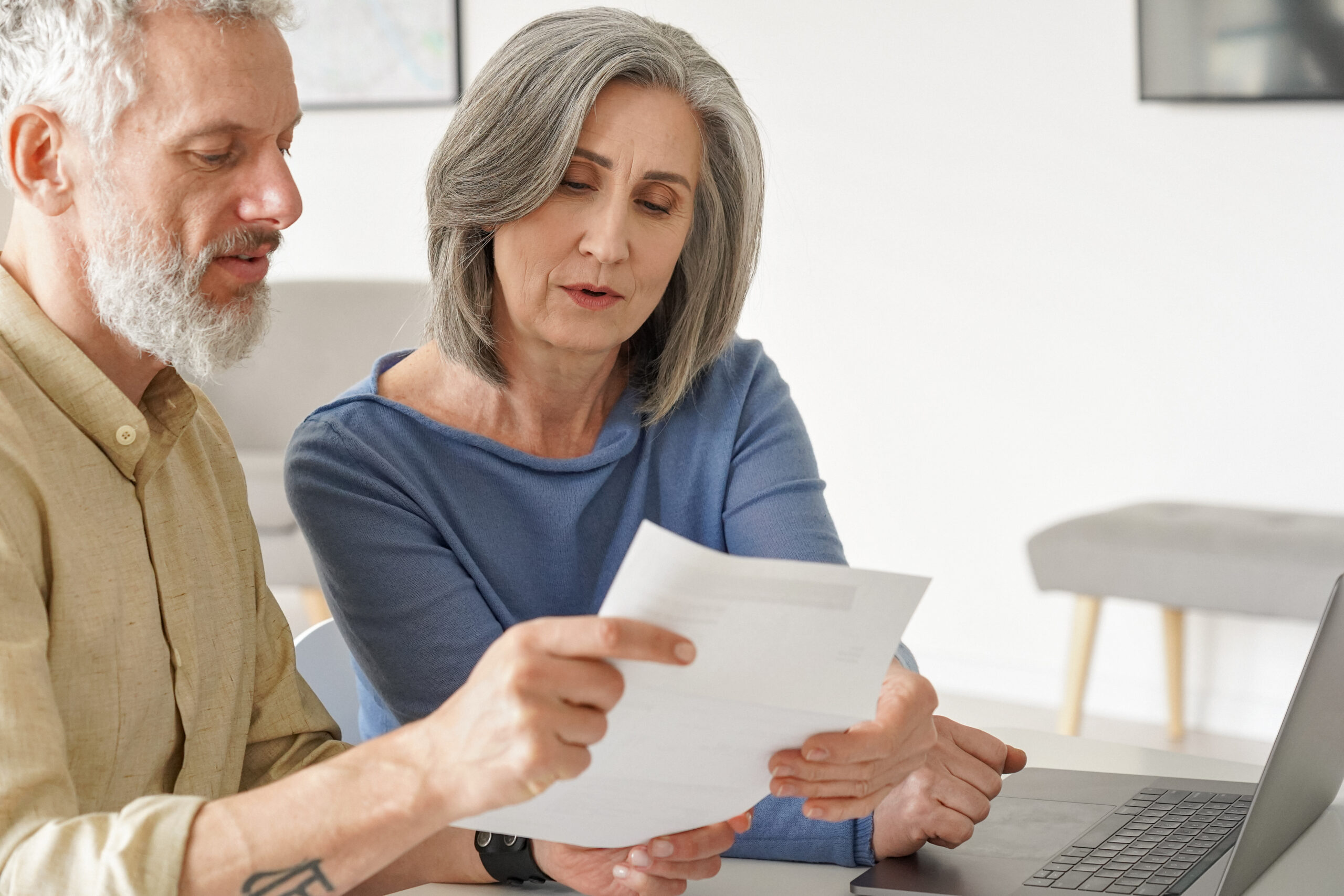 Older,Mature,Couple,Checking,Bank,Documents,Using,Laptop,At,Home.